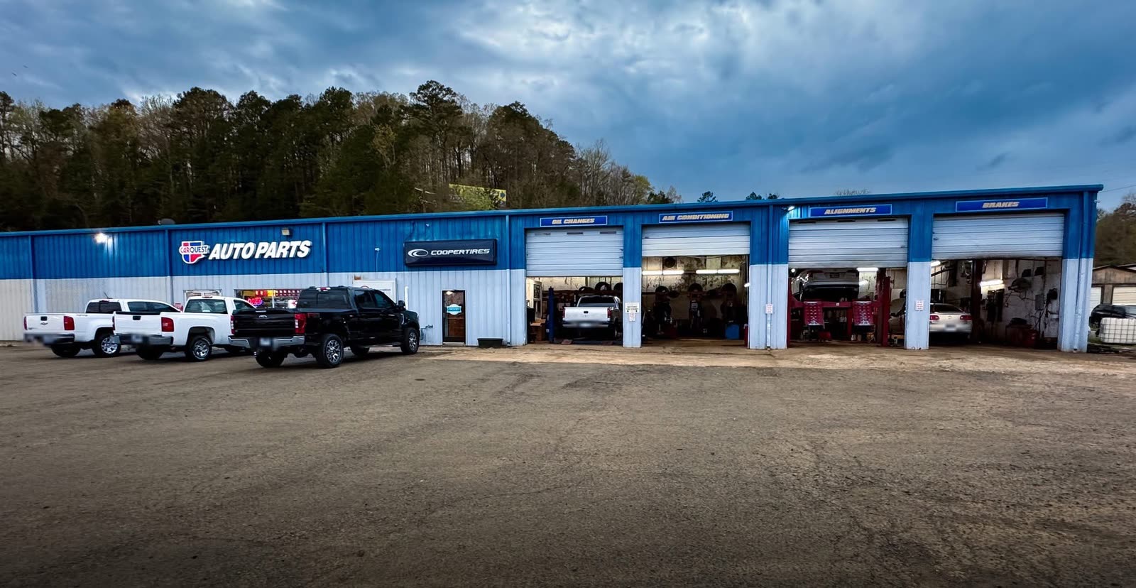 Garrett Automotive and Tire Center in Clinton, Arkansas: a blue shop building with four service bays and trucks parked out front